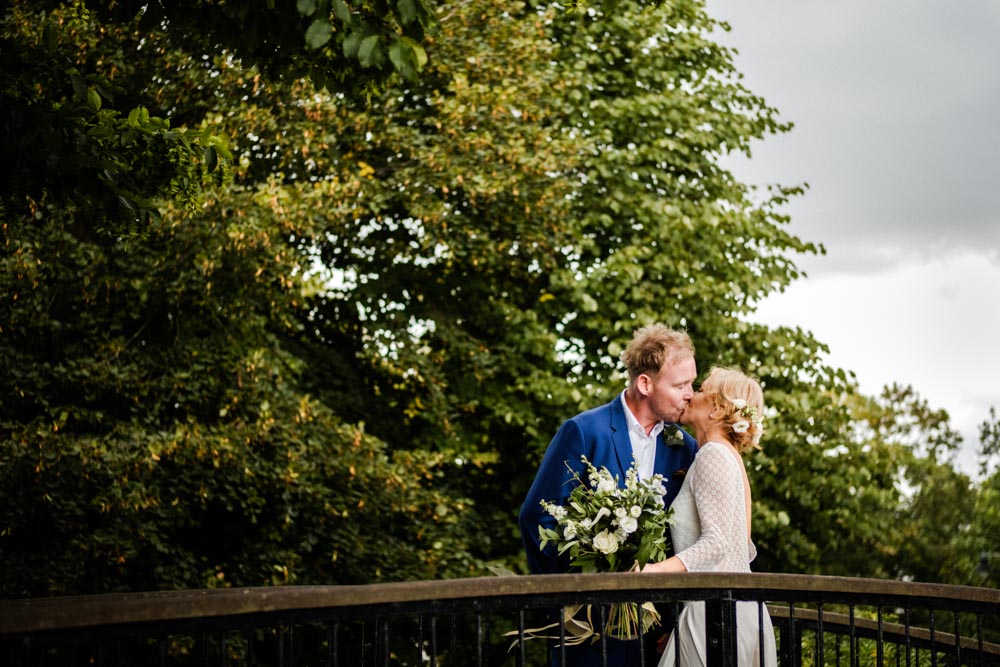 Bride and groom kiss on bridge in Canterbury